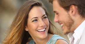 Funny couple laughing with a white perfect smile and looking each other outdoors with unfocused background