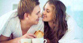 Couple enjoying one another while having breakfast in bed