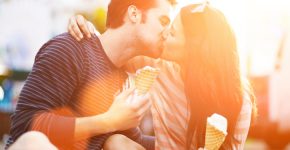 romantic couple kissing while holding ice cream